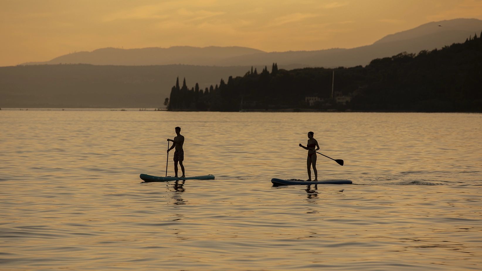 Coppia che usa il SUP a Garda durante la golden hour